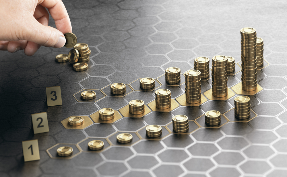 Human,Hand,Stacking,Coins,Over,A,Black,Background,With,Hexagonal